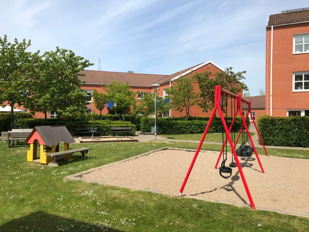 Image with a playground with swings and apartment buildings in Staffanstorp